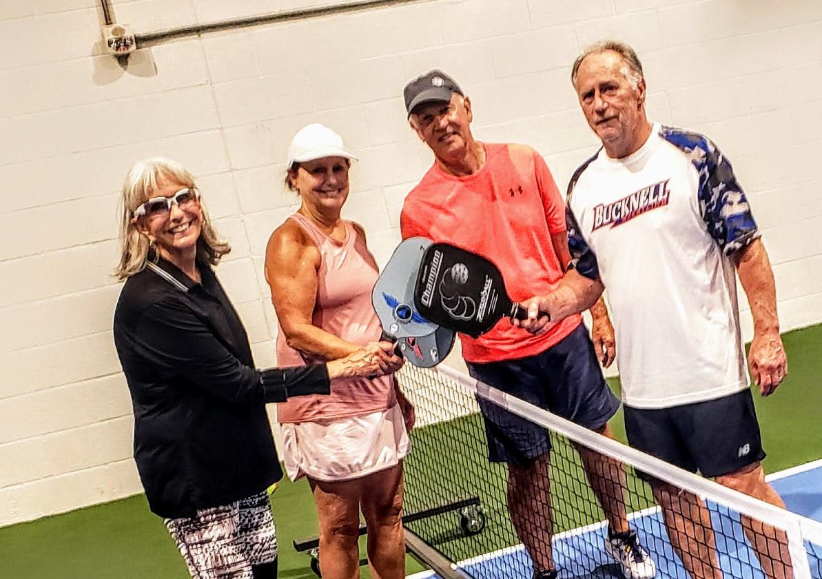 4 pickleball players holding pickleball paddles together